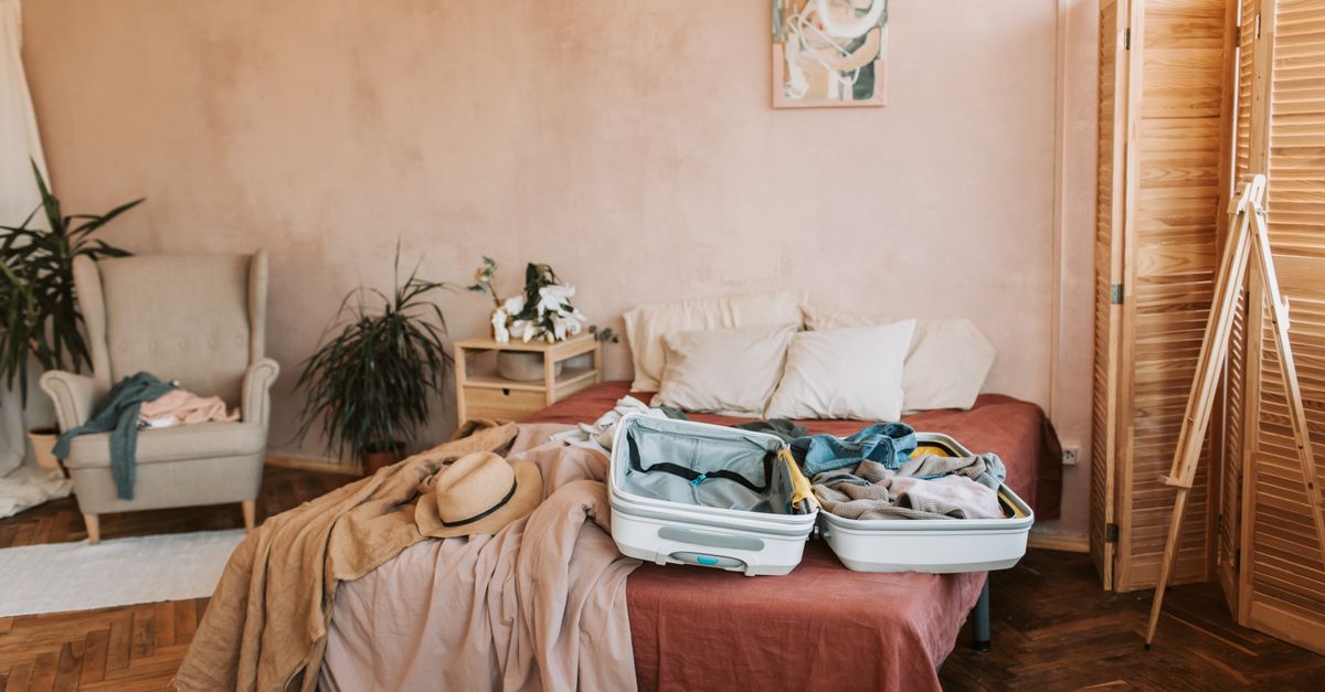 Maleta de cabina abierta sobre una cama con ropa doblada y artículos de viaje